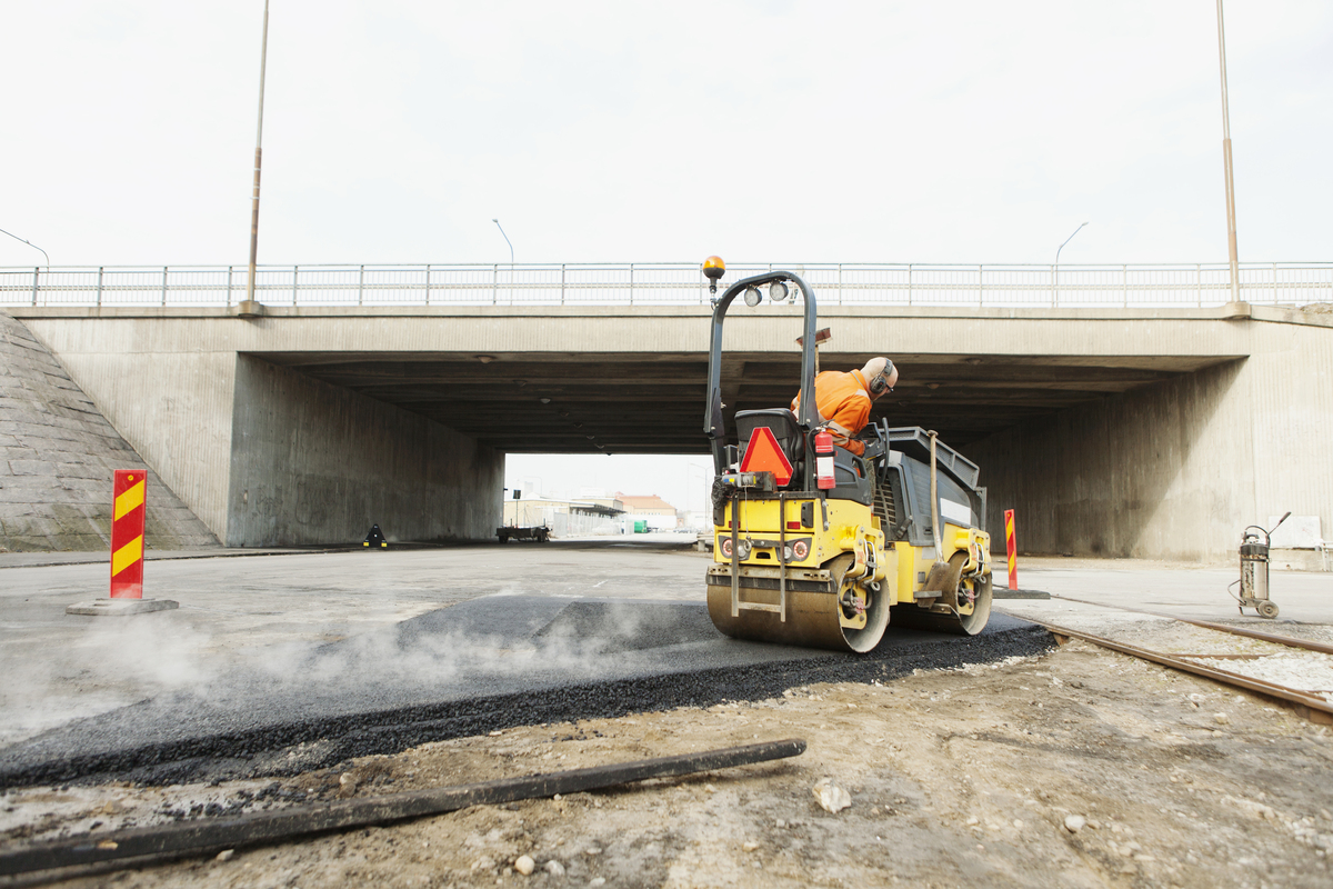 man driving steamroller on hot tar