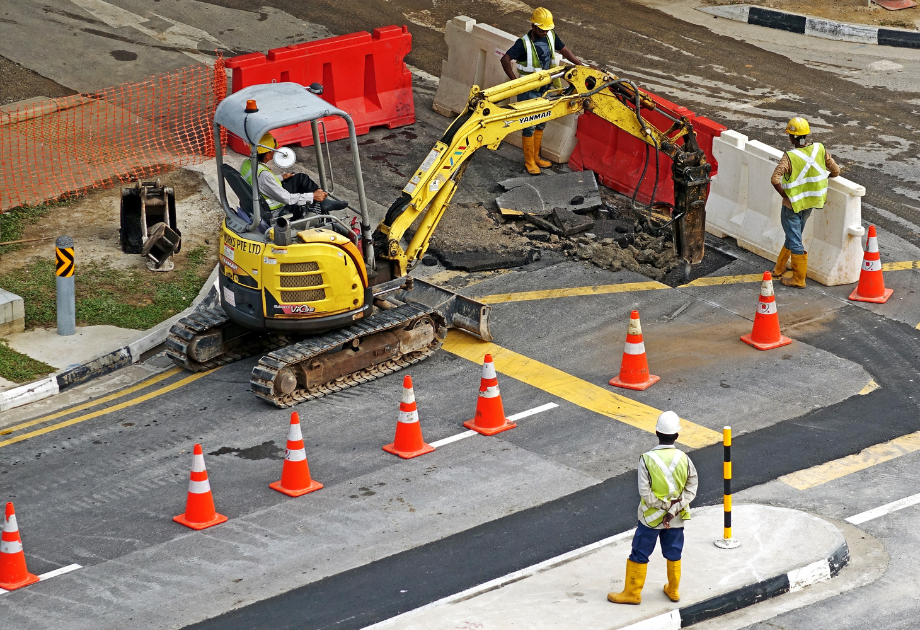 Construction workers digging up road with equipment